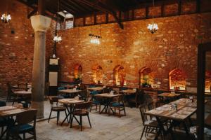 a dining room with tables and chairs and a brick wall at Fibar Hotel Zincirlihan in Aydın