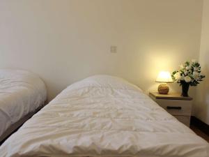 Cama blanca en un dormitorio con lámpara y flores en Appartement Rochefort, 3 pièces, 4 personnes - FR-1-246B-462, en Rochefort