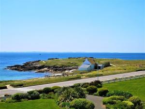 une route au bord de l'océan avec une maison sur une colline dans l'établissement Studio Quiberon, 1 pièce, 3 personnes - FR-1-478-97, à Quiberon