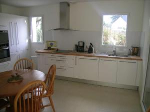 eine Küche mit weißen Schränken, einem Tisch und einem Fenster in der Unterkunft Villa Belz, 5 pièces, 8 personnes - FR-1-479-22 in Belz