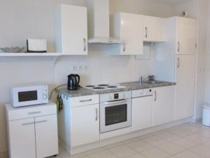 eine weiße Küche mit weißen Schränken und einer Mikrowelle in der Unterkunft Appartement Étel, 2 pièces, 4 personnes - FR-1-479-88 in Étel