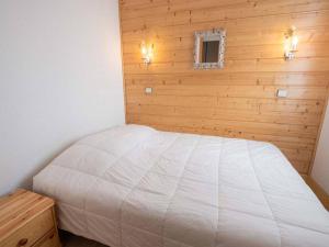 um quarto com uma cama branca numa parede de madeira em Appartement Valmorel, 3 pièces, 6 personnes - FR-1-291-823 em Valmorel