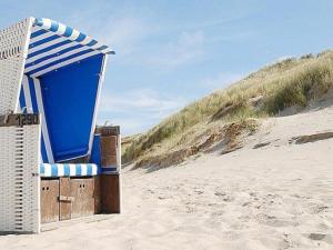 Una silla azul y blanca sentada en una playa en Appartement Merville-Franceville-Plage, 2 pièces, 4 personnes - FR-1-465-11, en Merville-Franceville-Plage