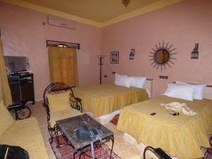 a hotel room with two beds and a table and chairs at Riad Nezha in Merzouga