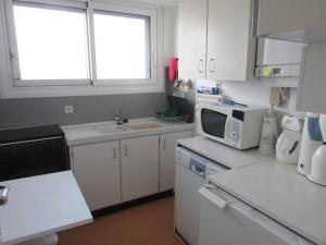 een keuken met witte kasten, een wastafel en een magnetron bij Studio Quiberon, 1 pièce, 3 personnes - FR-1-478-42 in Quiberon