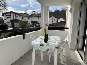 a table on a balcony with a vase of flowers on it at Appartement Cambo-les-Bains, 2 pièces, 2 personnes - FR-1-495-30 in Cambo-les-Bains