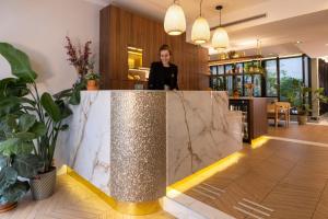 a woman standing behind a counter in a lobby at Hôtel La Canopée in Paris