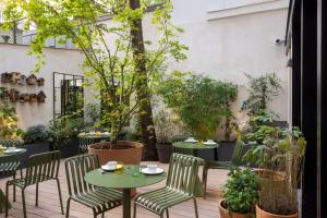 a patio with tables and chairs and potted plants at Hôtel La Canopée in Paris