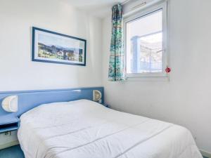 um quarto com uma cama com uma cabeceira azul e uma janela em Appartement Urrugne, 2 pièces, 4 personnes - FR-1-4-567 em Urrugne