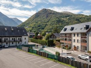 a town with a parking lot with mountains in the background at Appartement duplex Saint-Lary 6 pers, 2 ch, mezzanine, balcon - FR-1-296-302 in Saint-Lary-Soulan