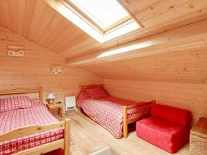 Cette cabane en rondins comprend 2 lits et un canapé rouge. dans l'établissement Studio Cauterets, 2 pièces, 4 personnes - FR-1-401-150, à Cauterets