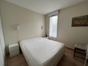 Un dormitorio con una cama blanca y una ventana. en Cambo-les-Bains: T3 Moderne avec Terrasse, Parc, Piscine, Parking, et Internet - 4 Couchages - FR-1-495-20, en Cambo-les-Bains