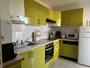 a kitchen with yellow cabinets and a white refrigerator at Appartement Cambo-les-Bains, 2 pièces, 2 personnes - FR-1-495-74 in Cambo-les-Bains