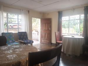 a living room with a table and chairs and windows at Blue Waxbill Lodge in Mwanza