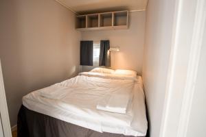 1 dormitorio pequeño con 1 cama con sábanas blancas en Koie Standard en Stranda