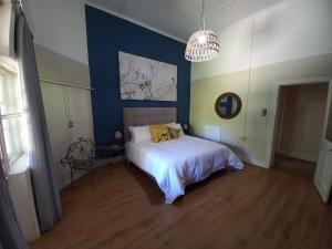 a blue bedroom with a bed and a chandelier at Karooland Gastehuis in Middelburg +3 photos