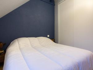 a white bed in a bedroom with a blue wall at Chalet triplex pour 7 pers. avec terrasse, parking, proche télécabine et commerces - FR-1-401-178 in Cauterets +1 photo