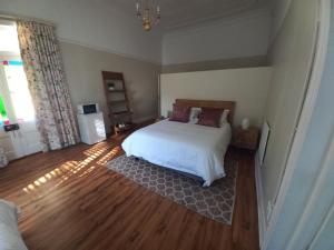 a bedroom with a white bed and a wooden floor at Karooland Gastehuis in Middelburg
