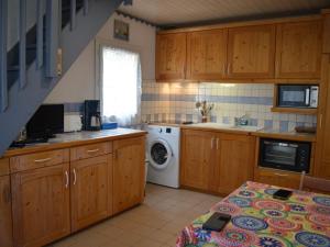 een keuken met houten kasten en een wasmachine en droger bij Maison Saint-Cyprien, 2 pièces, 6 personnes - FR-1-225D-95 in Saint-Cyprien