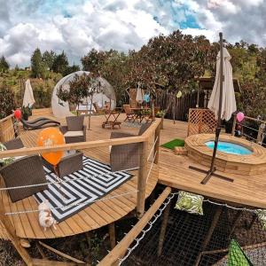 a deck with a pool and chairs and an umbrella at BubbleSky Glamping 40 min from Medellin in El Retiro