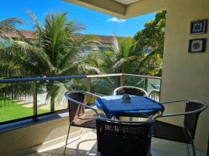 a table and chairs on a balcony with palm trees at Flat Praia Dos Carneiros in Tamandaré