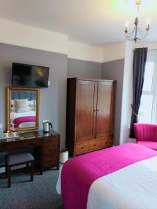 1 dormitorio con cama, escritorio y espejo en The Groveside Guest House, en Sidmouth