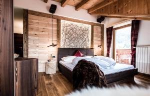 セルヴァ・ディ・ヴァル・ガルデーナにあるGarni Residence Soraiserの木製の壁のベッドルーム1室(ベッド1台付)