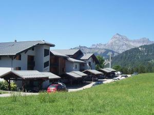 een gebouw met auto's voor het gebouw met een berg bij À Notre-Dame-de-Bellecombe: charmant appart 4-5 pers, terrasse sud, animaux OK - FR-1-505-56 in Notre-Dame-de-Bellecombe