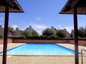 a large blue swimming pool with an umbrella at Appartement Erdeven, 2 pièces, 4 personnes - FR-1-479-106 in Erdeven