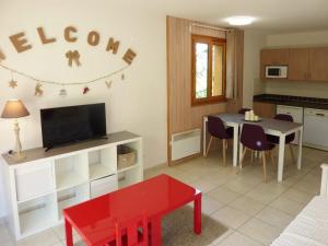 a living room with a red table and a kitchen at Appartement Les Orres, 2 pièces, 4 personnes - FR-1-322-370 in Les Orres