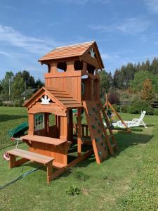 a wooden play house with a bench in the grass at Casa Familiar Puerto Varas in La Ensenada