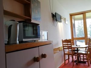 a kitchen with a microwave and a table with chairs at Studio Les Arcs 1800, 1 pièce, 4 personnes - FR-1-411-642 in Arc 1800