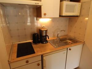 eine kleine Küche mit einer Spüle und einer Mikrowelle in der Unterkunft Appartement Bagnères-de-Luchon, 2 pièces, 4 personnes - FR-1-313-185 in Luchon