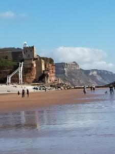 a group of people walking on a beach with a castle at The Groveside Guest House in Sidmouth