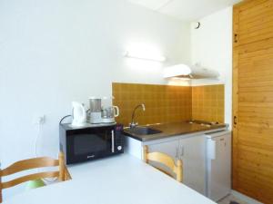 uma pequena cozinha com um lavatório e um micro-ondas em Studio Arette, 1 pièce, 4 personnes - FR-1-602-1 em Arette