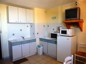 cocina con armarios blancos y TV en la pared en Appartement Arette, 2 pièces, 6 personnes - FR-1-602-53, en Arette