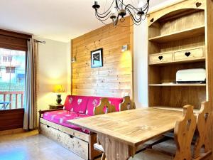 uma sala de jantar com uma mesa e um sofá rosa em Appartement Flumet, 2 pièces, 4 personnes - FR-1-505-110 em Flumet