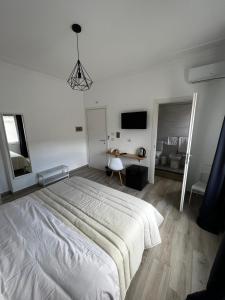 a white bedroom with a large bed and a desk at Dimora sicula guest house in Catania