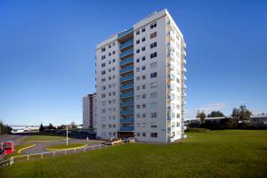 a tall white building with a green field next to it at Overlooking the city, bright & cozy - Free Parking (A2) in Reykjavík