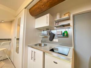 małą kuchnię z białymi szafkami i zlewem w obiekcie Mini Studio - Le Chabaud - Cannes centre w Cannes