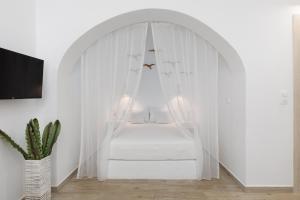 a white bedroom with a white canopy bed with a cactus at Blue Paradise in Ierápetra