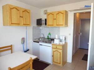 una pequeña cocina con electrodomésticos blancos y armarios de madera. en Studio Arette, 1 pièce, 4 personnes - FR-1-602-42, en Arette