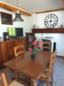 una mesa de comedor con un jarrón de flores. en gite rural de l ource 