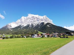 a mountain in front of a green field with a town w obiekcie Apartment Almglück w mieście Ehrwald