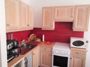 a kitchen with wooden cabinets and a red wall at Studio cabine 4 pers. La Mongie, centre station, près des pistes - FR-1-404-333 in La Mongie