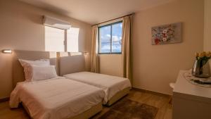 a small bedroom with two beds and a window at Refugio do Sol - Madeira Inn Group in Calheta