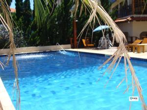 una piscina azul con sombrilla y sillas en São Roque Park Hotel, en São Roque