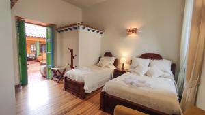 a bedroom with two beds and a door to a patio at Casona 1865 in Ráquira