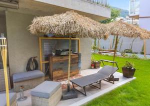 een patio met een rieten parasol, 2 stoelen en een tafel bij Bel appartement avec parking souterrain sur place in Martigny-Ville