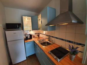 cocina con armarios azules y nevera blanca en Appartement Rayol-Canadel-sur-Mer, 2 pièces, 4 personnes - FR-1-100-260, en Rayol-Canadel-sur-Mer